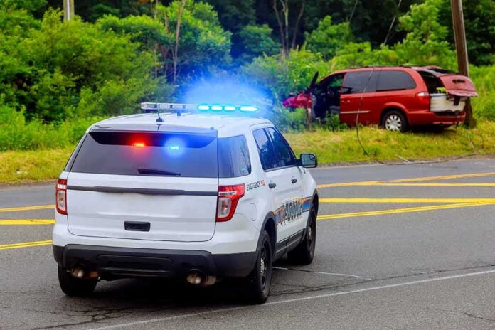 shutterstock_1119061259 Police SUV with flashing lights at roadside crash scene