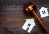 Housing Cash Mystery Rattles City Hall Judge's gavel with paper house cutouts on wooden table