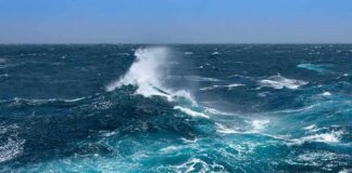 Ocean waves crashing with white spray under a clear blue sky