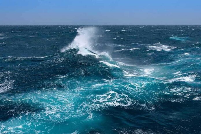 Ocean waves crashing with white spray under a clear blue sky