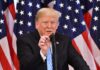 Donald Trump speaking at a podium with American flags in the background