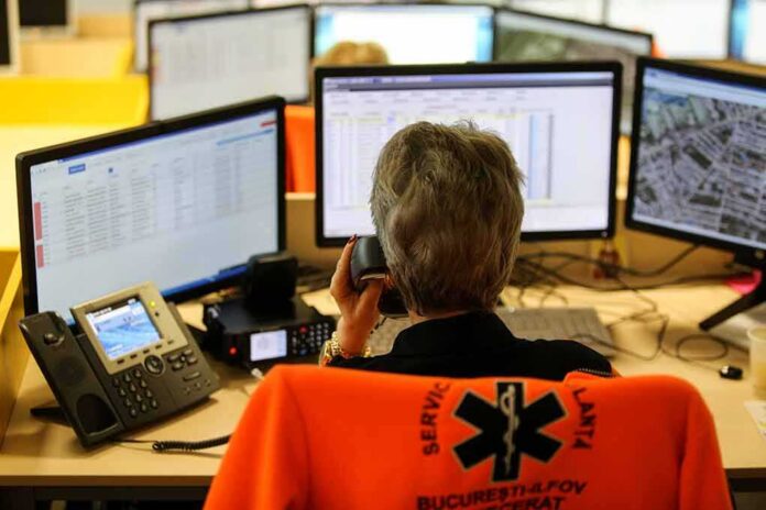 Emergency dispatcher at workstation with multiple monitors and phone