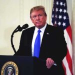 Trump Honors Musk and Five Tech Leaders man at podium with microphone and US flag