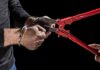 Hands in handcuffs being cut with red bolt cutters