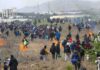 Border Rush Builds Before Midterms Large crowd of people walking through a field with small fires