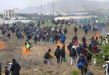 Border Rush Builds Before Midterms Large crowd of people walking through a field with small fires