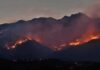 Gusts Hit 70 – Evacuation Prep Now Wildfire burning along mountain slopes at dusk