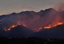 Gusts Hit 70 – Evacuation Prep Now Wildfire burning along mountain slopes at dusk