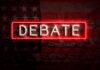 Neon sign reading debate on a brick wall
