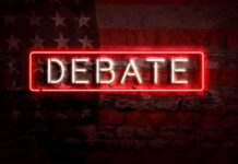 Iowa House Candidates Clash Over Tariffs, Taxes Neon sign reading debate on a brick wall