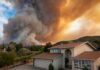 Blaze Jumps Neighborhood Lines Fast Suburban house under towering wildfire smoke plume