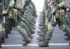 Soldiers in green uniforms march in formation