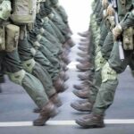 Soldiers in green uniforms march in formation
