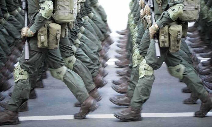 shutterstock_2031559106 Soldiers in green uniforms march in formation