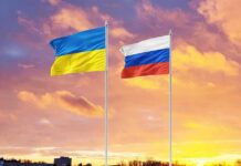 Ukrainian and Russian flags on poles at sunset