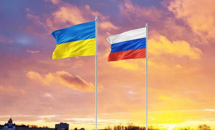 Ukrainian and Russian flags on poles at sunset