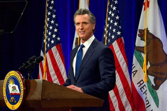 shutterstock_2137542759 Man in suit speaking at a podium with American and California flags