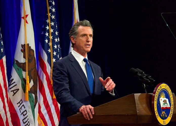 shutterstock_2138866237 Gavin Newsom speaking at a podium with U.S. and California flags