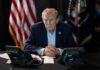 Shock Move: Trump Eyes Ambassador Ouster Donald Trump seated at a table between two desk phones
