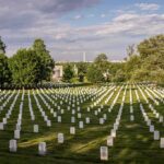 Rows of white headstones in a cemetery under a partly cloudy sky