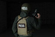 Shocking Beating Caught On Camera Press photographer in helmet and vest holding a camera
