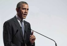 Past Blast Haunts Obama Rally Plans Rob Nabors speaking at a podium with microphones