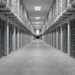 Prison corridor lined with barred cells on both sides