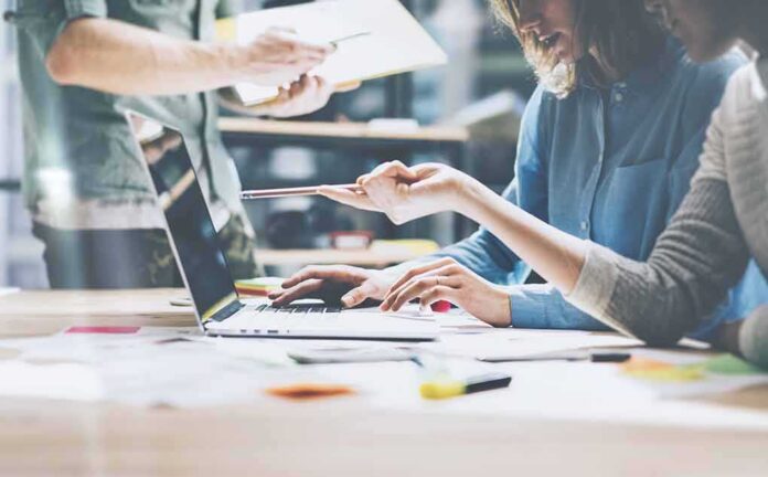 Team collaborating at a laptop in a modern workspace